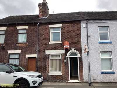 Red-brick terrace with an arched doorway and a white car outside